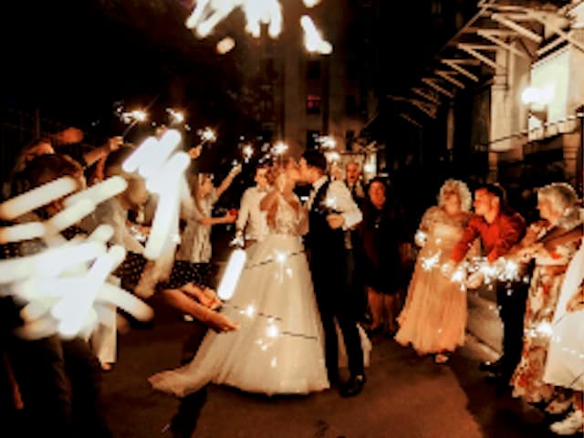 Bride and groom kissing during a sparkler send-off surrounded by their guests